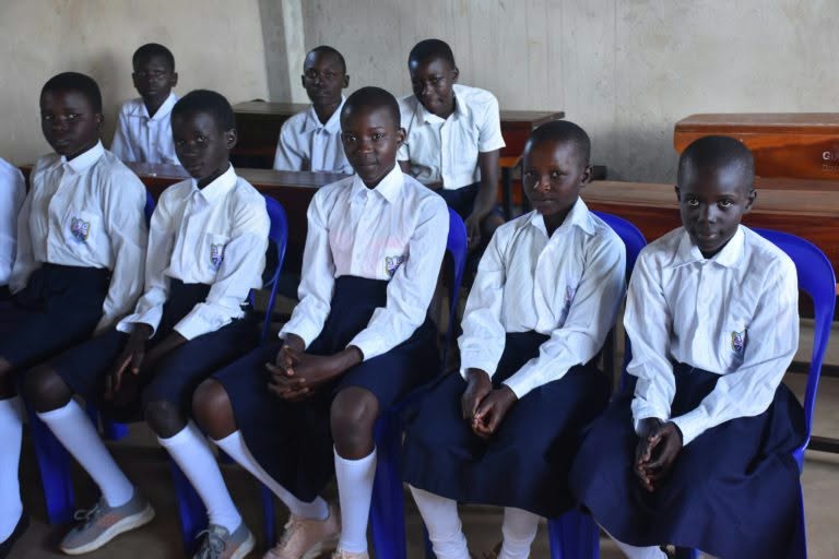 Members of the Kweyo Primary School Peace Club seated in their classroom in school uniform